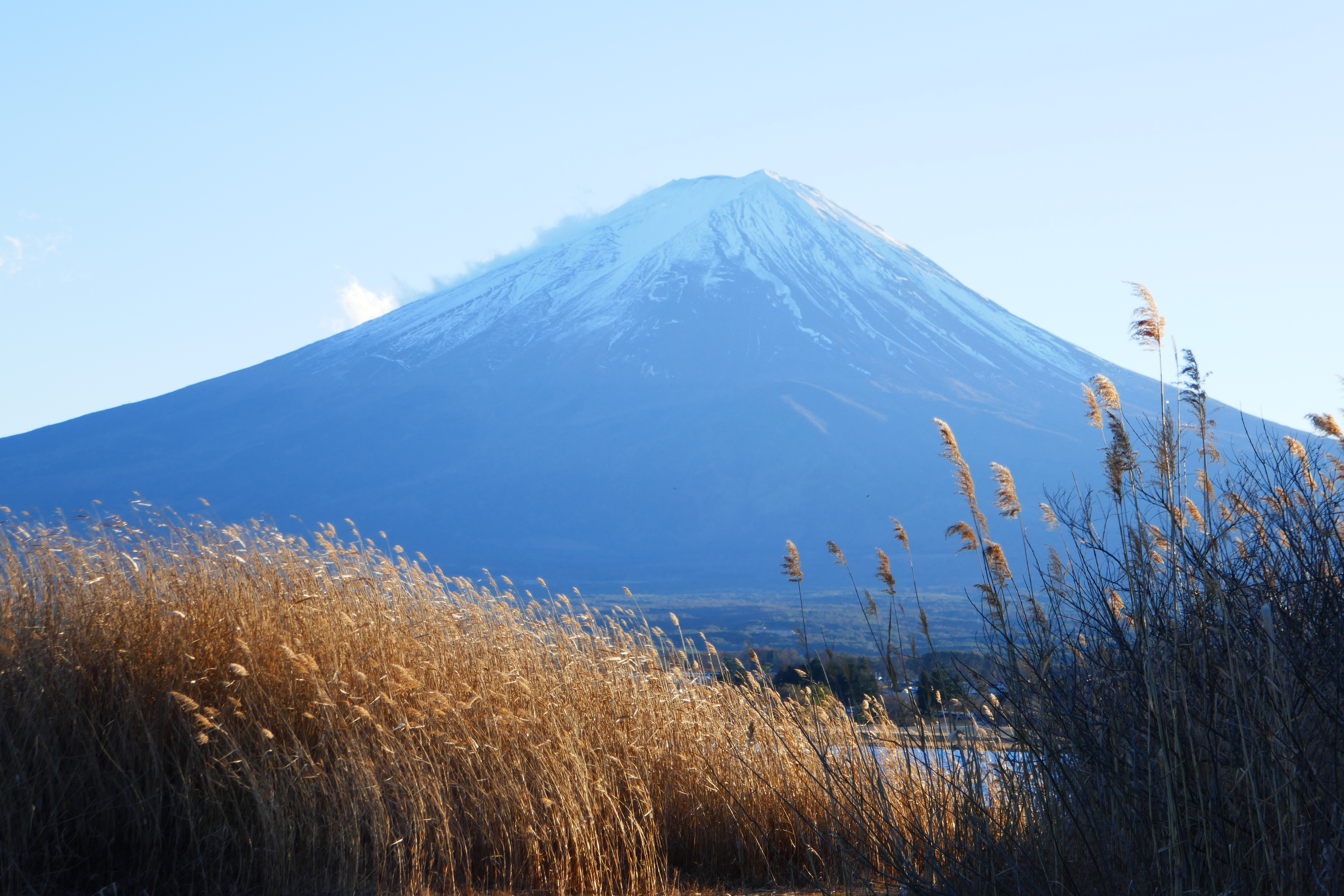 Mount Fuji photographed at a distance under a pale sky.